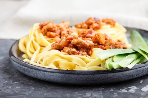Tagliatelle bolognese pasta with minced meat on a black concrete background. side view, close up