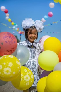 Happy schoolgirl with colourful balloons on the first day of school, Issyk-Kul region, Kyrgyzstan,
