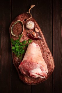 Raw pork knuckle, on a wooden chopping board, with spices, close-up, top view, no people