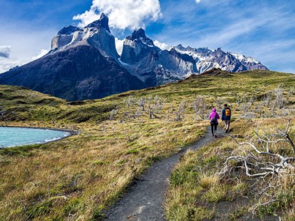 Hikers on small path to viewpoint Mirador Cuernos above lake Nordenskjöld, burned trees, Paine