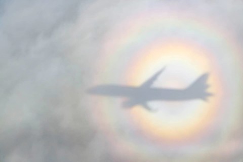 An aeroplane casts a shadow on a cloud, silhouette, halo rainbow. Germany