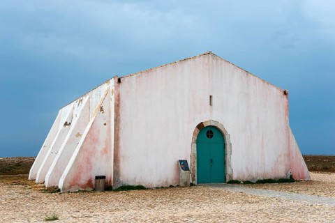 A solitary, weather-beaten building with a white façade under a cloudy sky, Historic Assembly and