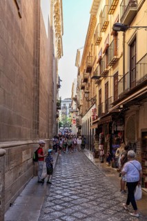 People stroll through a narrow street with shops in the old town, Granada