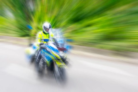 Policeman on a motorbike driving fast along the road, the speed is emphasised by the motion blur,