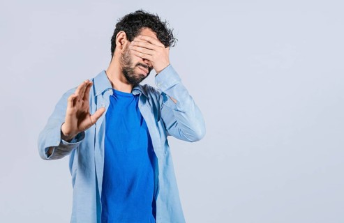 Scared confused man closing eyes with palm of hand isolated
