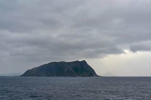An island in the sea under a cloudy, gloomy sky, Alesund, Fylke, Norway, Europe
