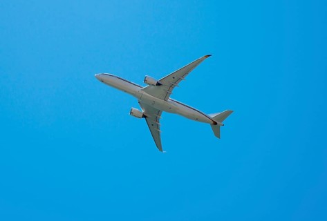 A large aircraft flies through a clear blue sky, Airbus A350 with the registration number 10 plus