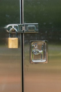 Close-up of stainless steel door on a utility cabinet locked with a brass padlock, Quebec, Canada,