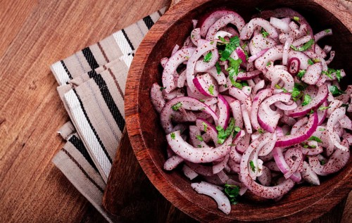 Chopped red onion, with sumac and herbs, in a bowl, pickled Spanish onion, close-up, top view