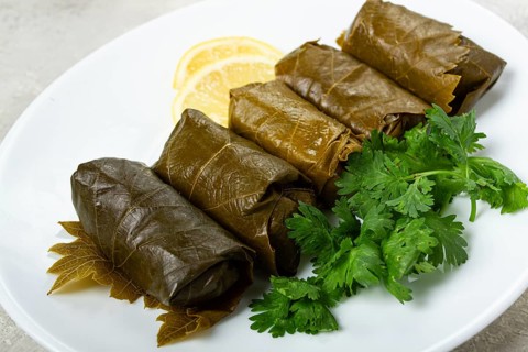 Dolma, minced meat with rice, in grape leaves, rolls with minced meat, on a white plate, top view,