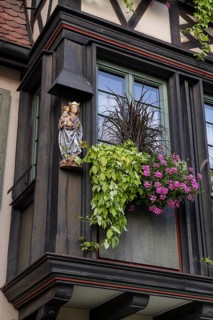 Decorative floral decoration with a statue of the Virgin Mary on a historic half-timbered house in