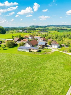 Aerial view of an extensive meadow landscape with a village and farmhouses, glass fibre