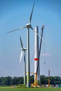 Erection of the tower of a wind power plant in a wind farm near Issum, 9 older wind turbines from