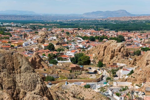 Panorama of a town with red roofs in a mountainous landscape under a blue sky, view from the