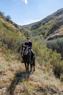 Traditional Kyrgyz eagle hunter with eagle in the mountains, hunting on horseback, near Kysyl-Suu,