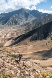Traditional Kyrgyz eagle hunter hunting in the mountains in a dry landscape, near Kysyl-Suu, Issyk