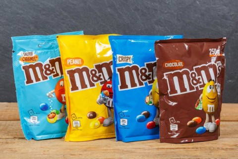 Various types of M&M's chocolate lentils from Mars Inc. on a wooden board
