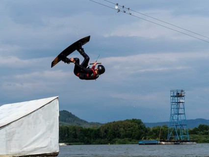 Man jumping with wakeboard over obstacle, somersault, water sports, water skiing and wakepark,