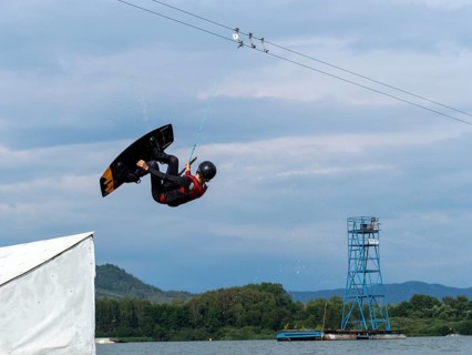 Man jumping with wakeboard over obstacle, somersault, water sports, water skiing and wakepark,
