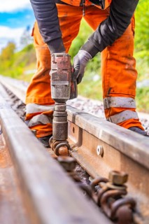 A construction worker uses a tool to fix the railway rails on the track, rail welding, track