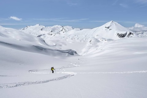 Lone ski tourer in mountain landscape with snow, summit Mittaghorn and Wildhorn, ascent to