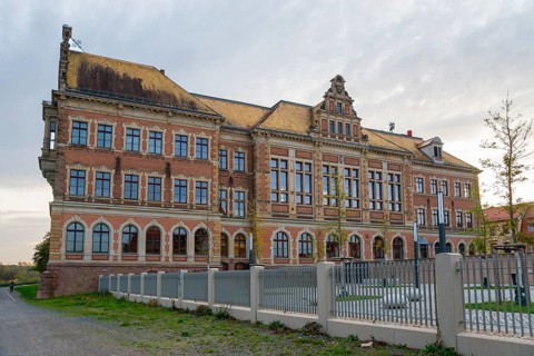 Imposing building with brick walls, large windows and fenced-in courtyard, St. Augustin Grammar