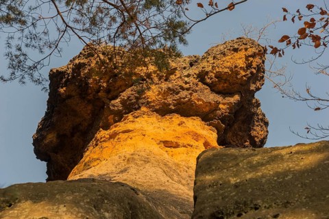 Close-up of a bright orange rock formation with trees and blue sky, Kokorinske poklicky rock