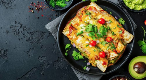 Plate of enchiladas with a side of salsa and guacamole. Wooden table with bowls of various sauces,