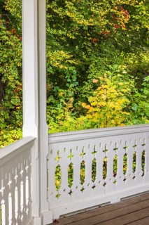 White wooden railing with joinery on a terrace with trees in autumn colours