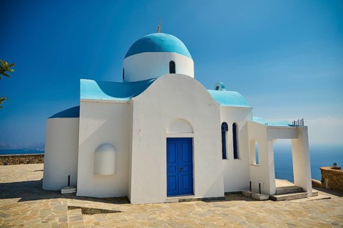 White and blue church with striking blue entrance and sea view in the background, Church of