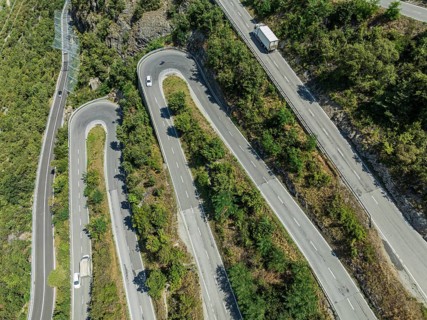 Mountain pass road with multiple hairpins, water pipeline, aerial view, drone shot. Valais,