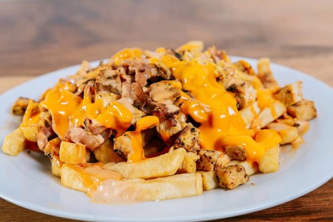 Traditional chicken nachos with melted cheese. Plate of chicken nachos with potatoes and melted