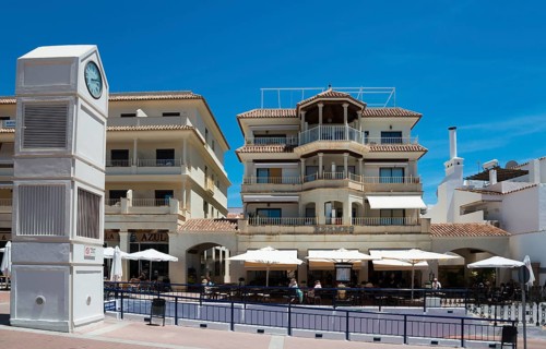 Clock tower and Mediterranean buildings with balconies and cafés in sunny weather, Plaza de España,