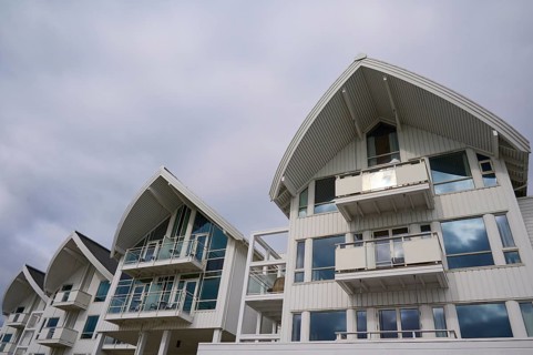 A modern residential building with several balconies and glass fronts under a cloudy sky, Molde,
