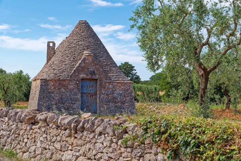 A detached trullo, round house with a stone roof, on the edge of the southern Italian town of