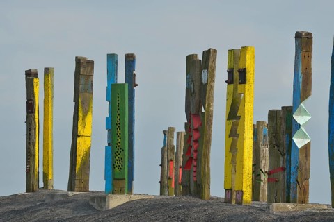 A creative art installation of colourfully painted wooden posts with abstract patterns against a