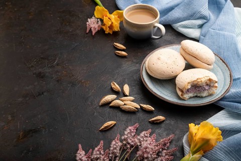 Meringues cakes with cup of coffee on a black concrete background and blue linen textile. Side