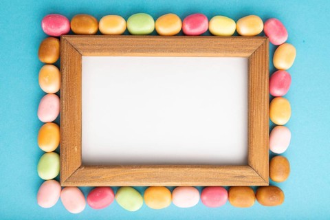 Composition with candies and wooden frame on blue pastel background. copy space, top view, flat
