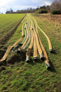 Long lines of irrigation hose pipes laid out on the ground, Shottisham, Suffolk, England, UK