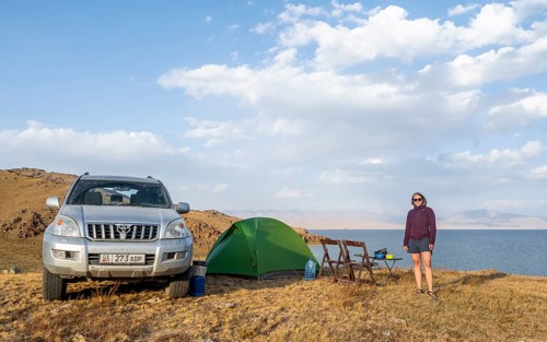 Hiker in front of a tent, camping in the highlands, Song Kul mountain lake, Naryn region,