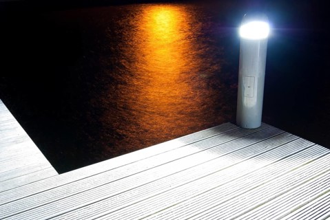 Pier with illuminated lamp and light reflections in the water at night, artistic, harbour village