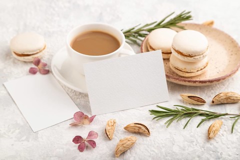 White business card mockup with cup of coffee, almonds and macaroons on gray concrete background.
