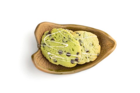 Green cookies with chocolate and mint on leaflike ceramic plate isolated on white background. top