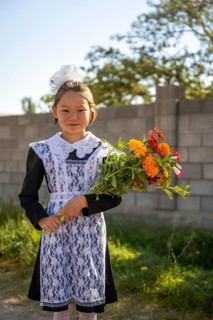 Schoolgirl with a bouquet of flowers on her first day at school, Issyk-Kul region, Kyrgyzstan, Asia