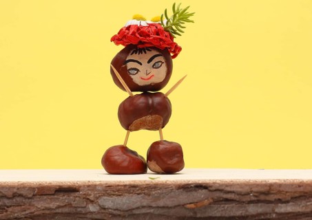 Funny chestnut figure with hat standing in front of a yellow wall, North Rhine-Westphalia, Germany,