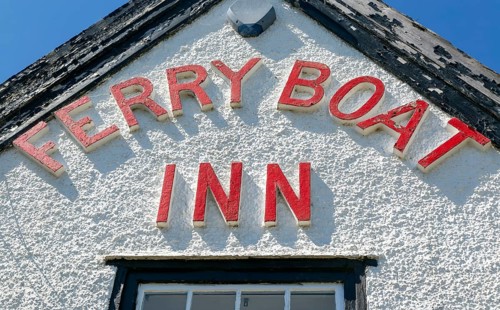 Red lettering detail of pub sign Ferry Boat Inn, Felixstowe Ferry, Suffolk, England, UK