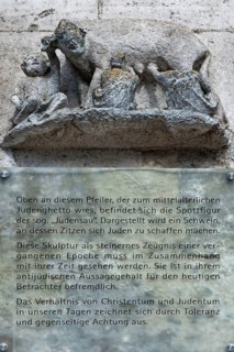 Medieval mocking figure of the so-called Judensau at St Peter's Cathedral, below information sign