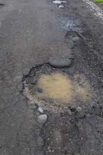 Pothole filled with rainwater on wet black asphalt road surface in spring, Montreal, Quebec,