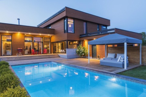 Rear of modern cube style home with stained horizontal wood cladding, in-ground swimming pool and