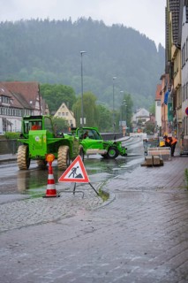 A construction site in a town in the rain, construction workers and excavators working on a wet